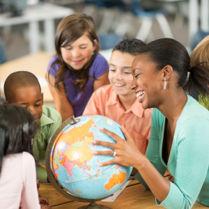 Students and teacher gathered in circle in classroom around globe