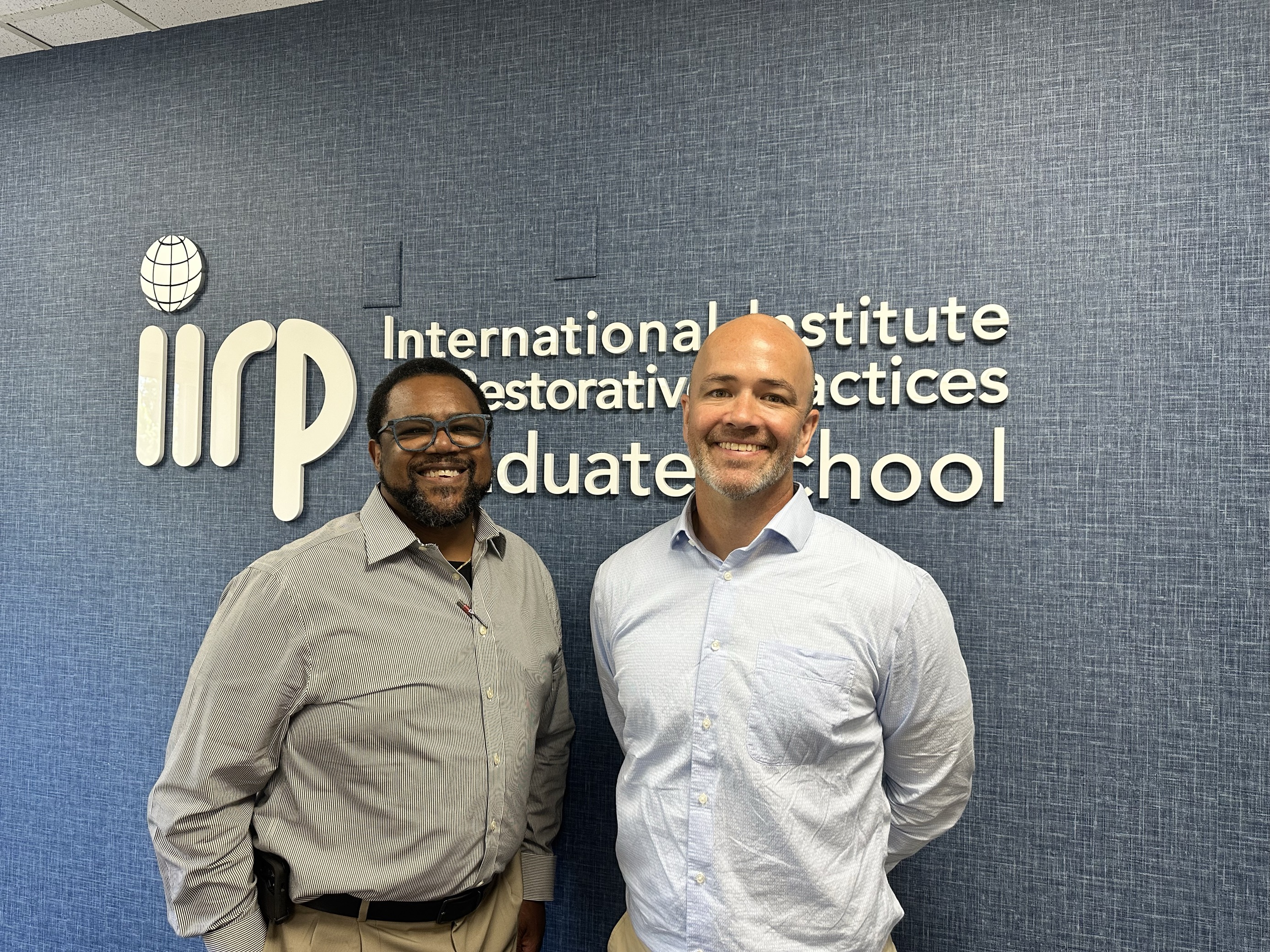 Michael Washington and Doug Judge pose in front of IIRP logo